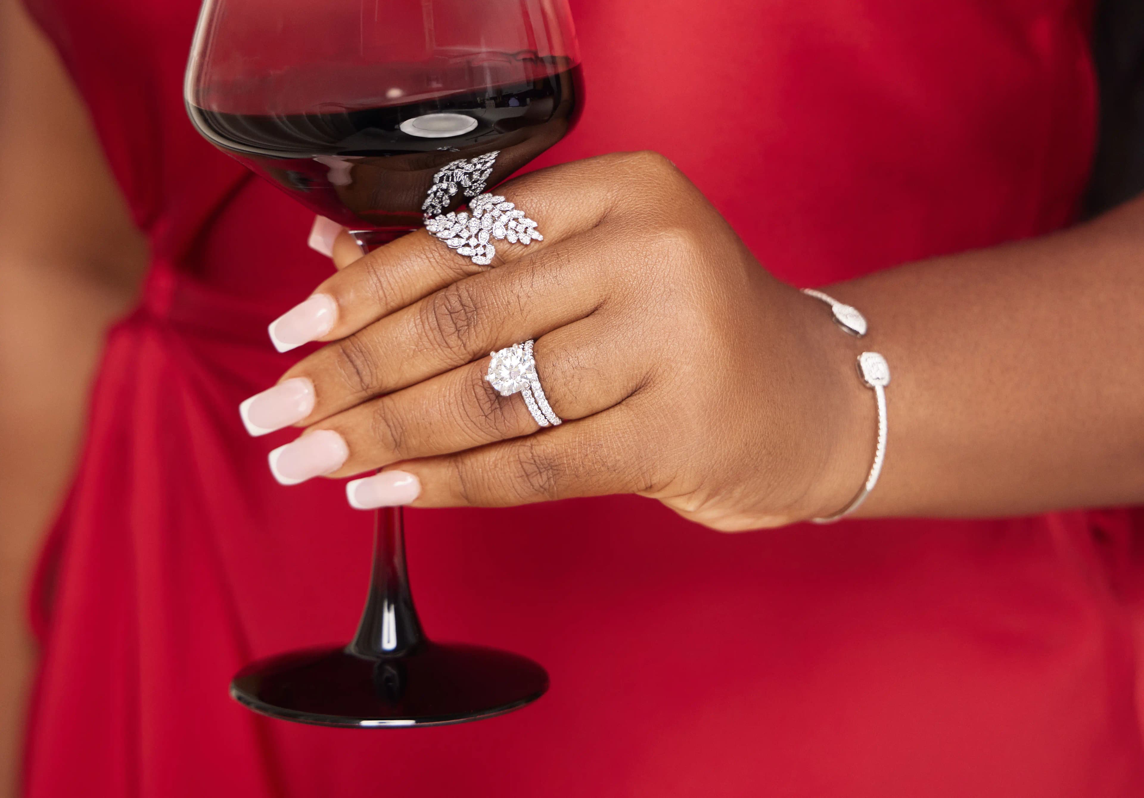 Lady holding a wine glass with two white gold rings and bangle